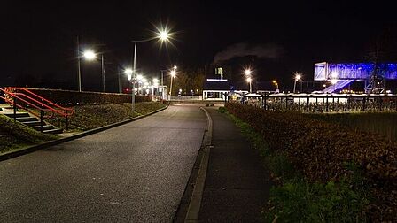 Station Barneveld Noord in de nacht. Er zijn meerdere lantaarnpalen bij de perrons. De fietsenstallingen en de traverse zijn fel verlicht. Er is geen treinverkeer meer