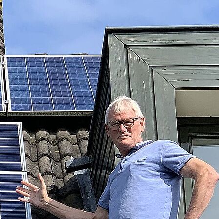 Energieambassadeur Ad van Rooijen op het dak bij zonnepanelen